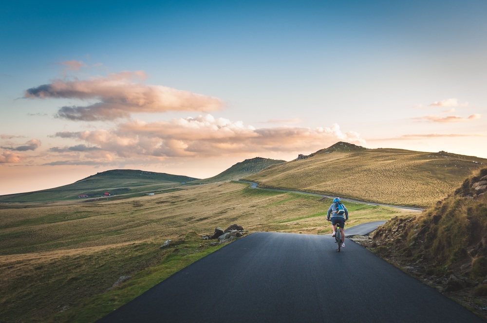 Person biking on road that winds through mountains