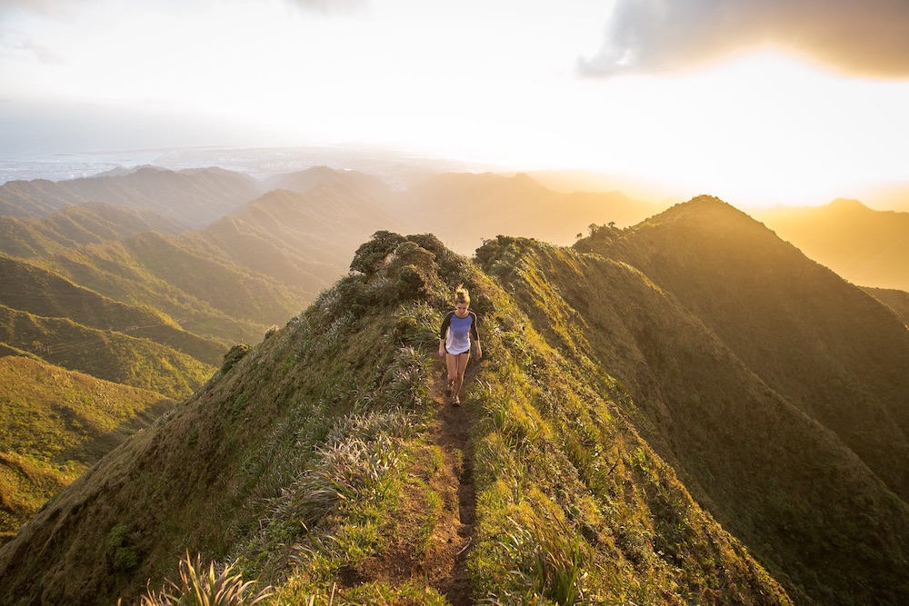 Person hiking on trail that goes along tops of mountains