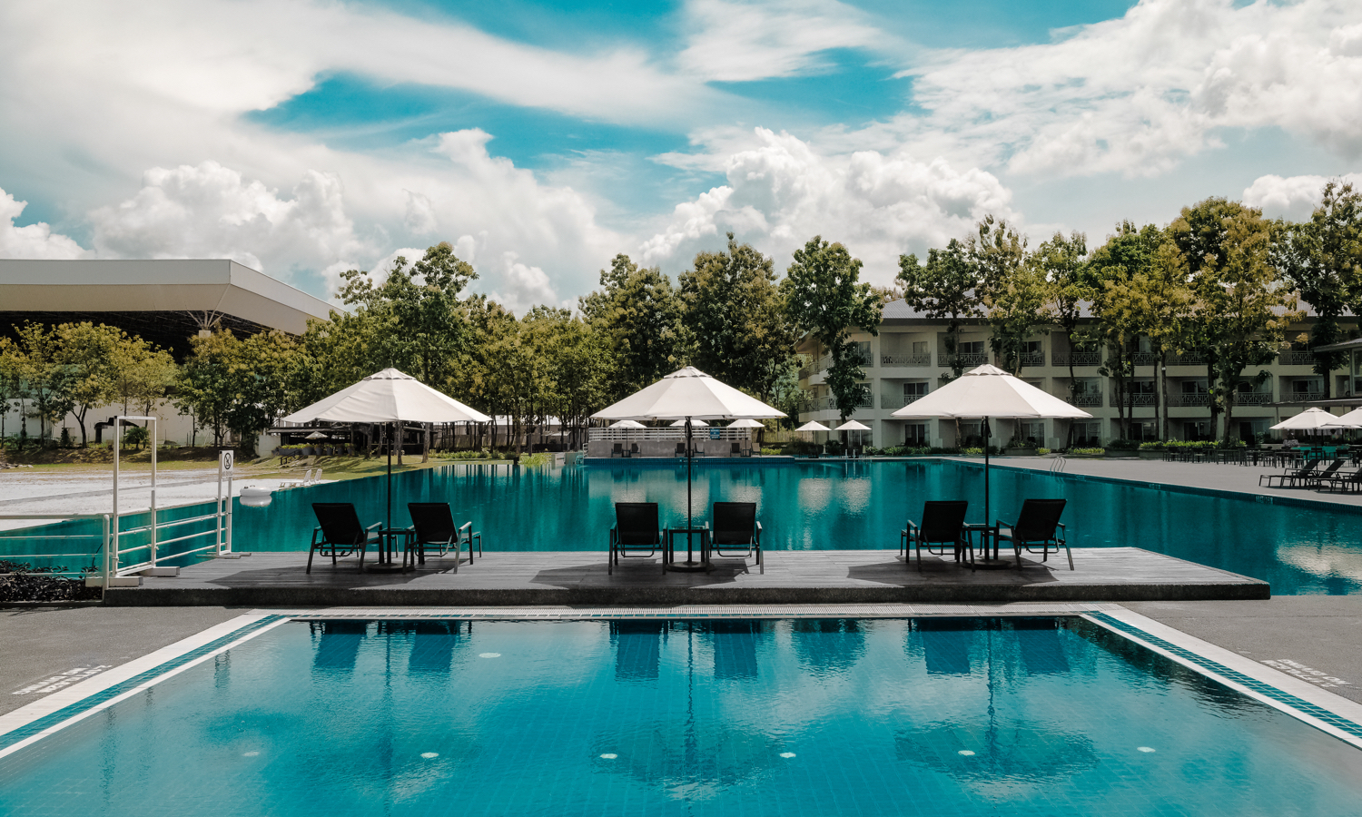 Hotel pool with pool chairs and umbrellas during day